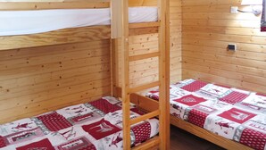 Habitación con literas, paredes de madera y una escalera.