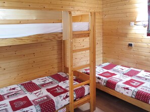 Habitación con literas, paredes de madera y una escalera.