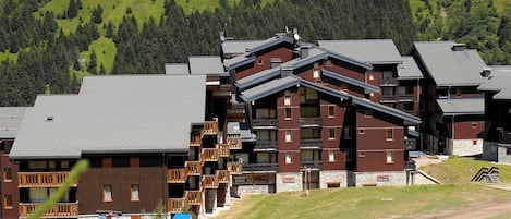Un hôtel à plusieurs étages doté d'un télésiège, entouré de collines verdoyantes et d'arbres.