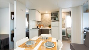 Een ruimtelijk ingerichte leefruimte met een eethoek, kitchenette en een slaapgedeelte.