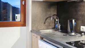 Une cuisine avec une fenêtre, un évier, un lave-vaisselle et une cuisinière.