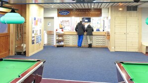 Une salle de billard comprenant un comptoir d’accueil, des poutres en bois au plafond et une table de billard.