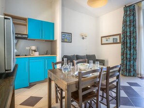 A compact kitchen with a refrigerator, a coffee maker, and a dining table with chairs.