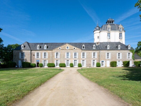A large, historic building with a central courtyard, symmetrical windows, and a prominent tower.