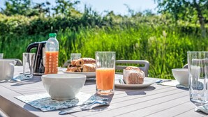 A breakfast table set outdoors with a view of lush greenery. - Rés. Odalys Référence Horizon Morgat by Interhome (Crozon-Morgat)