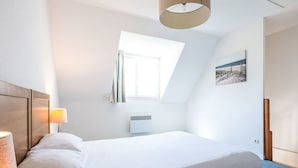 A bedroom with a bed, a lamp, a window, and a painting on the wall. - Rés. Odalys Référence Horizon Morgat by Interhome (Crozon-Morgat)