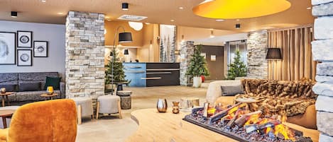 A modern lobby with a stone accent wall, a reception desk, a fireplace, and a seating area with a sofa and chairs.