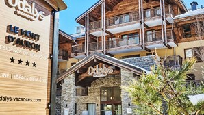 Un hôtel à la façade en bois, doté de nombreux balcons et d’une entrée en pierre.