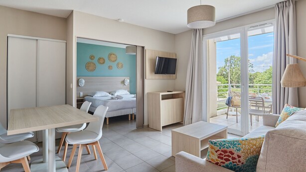 Ein modernes Hotelzimmer mit Bett, Schreibtisch, Essbereich und einem Balkon mit Blick.