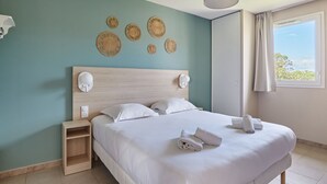 Ein ordentlich bezogenes Bett mit weißen Leinen und Handtüchern, ein hölzernes Kopfende und eine Wand mit Wandbehängen.