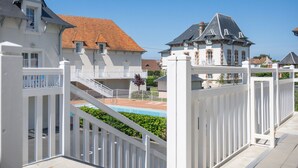 Een omheind woongebied met een zwembad, witte hekken en huizen met verschillende dakstijlen.