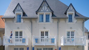 A multi-story building with a white facade, multiple balconies, and a sign indicating a reception area. - Odalys Référence Le Domaine des Dunettes by Interhome (Cabourg)