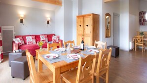 A dining area with a wooden table set for four, surrounded by wooden chairs. - Odalys Référence L'Ours Blanc by Interhome (Les Deux Alpes)