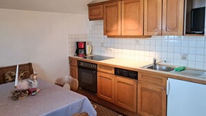 A compact kitchen with wooden cabinets, a dishwasher, a coffee maker, and a sink.