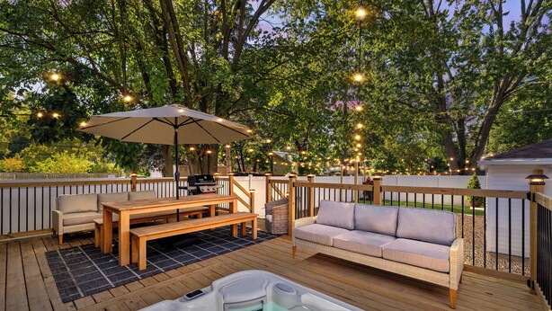 A wooden deck with a hot tub, outdoor furniture, and string lights. - Cozy, Beautiful Birmingham 4BR/2BA Getaway! (Birmingham)