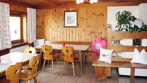 Un interior de madera con una mesa de comedor, sillas, un banco y una planta.