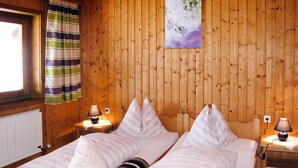 Una habitación de cabaña de madera con dos camas, cortinas a rayas y un cuadro en la pared.