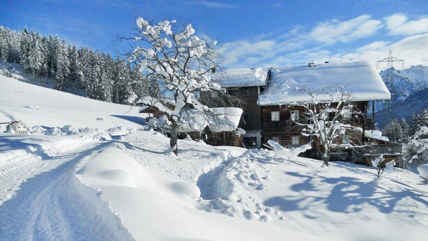 Un paisaje nevado con una cabaña de madera y cielo despejado.