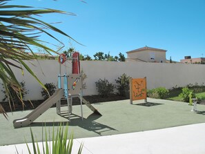 Explore the outdoor play area with a slide, climbing structure, and a table with a chair.