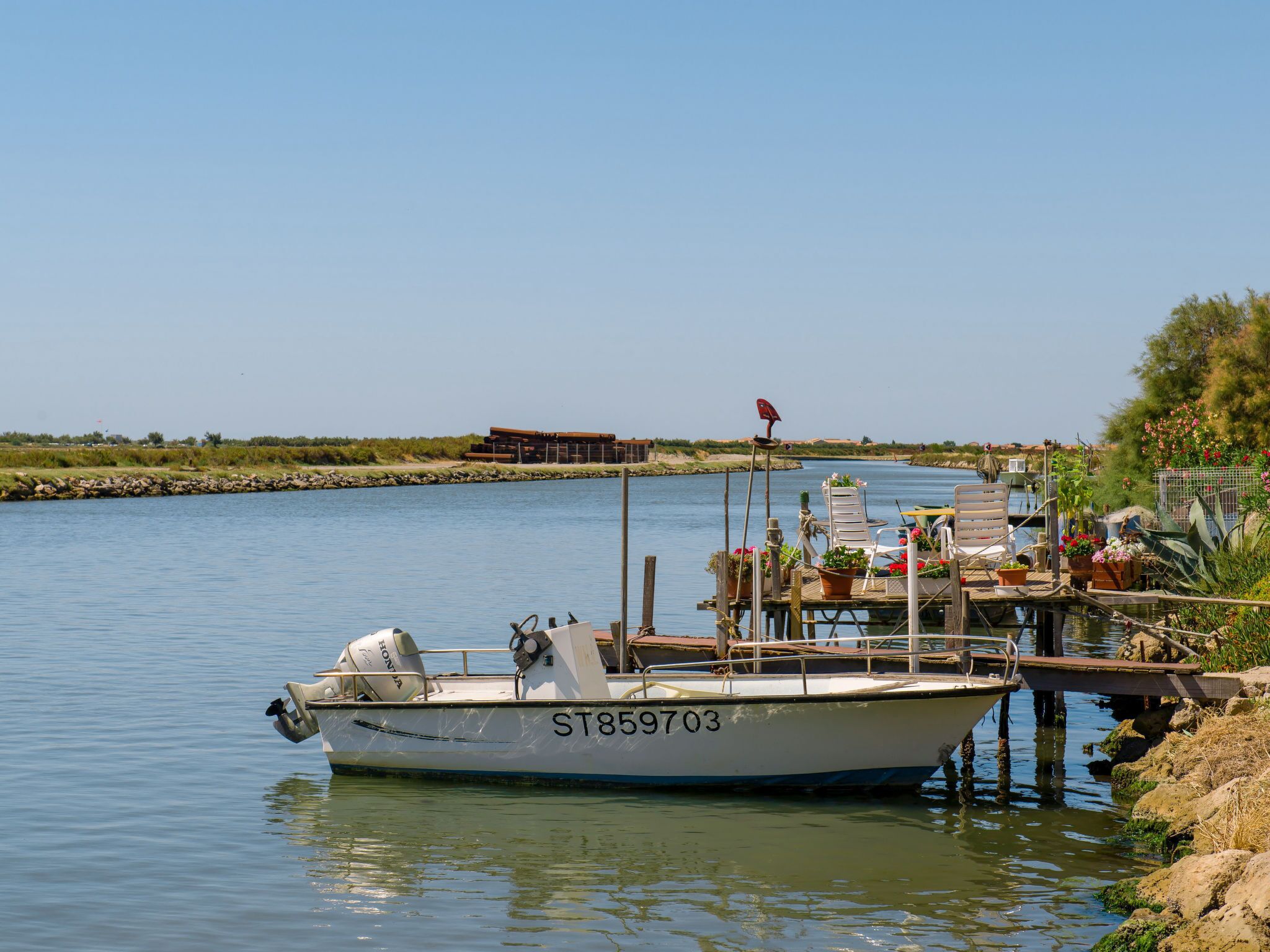 A boat docked at a pier with a clear view of the water and distant shoreline.