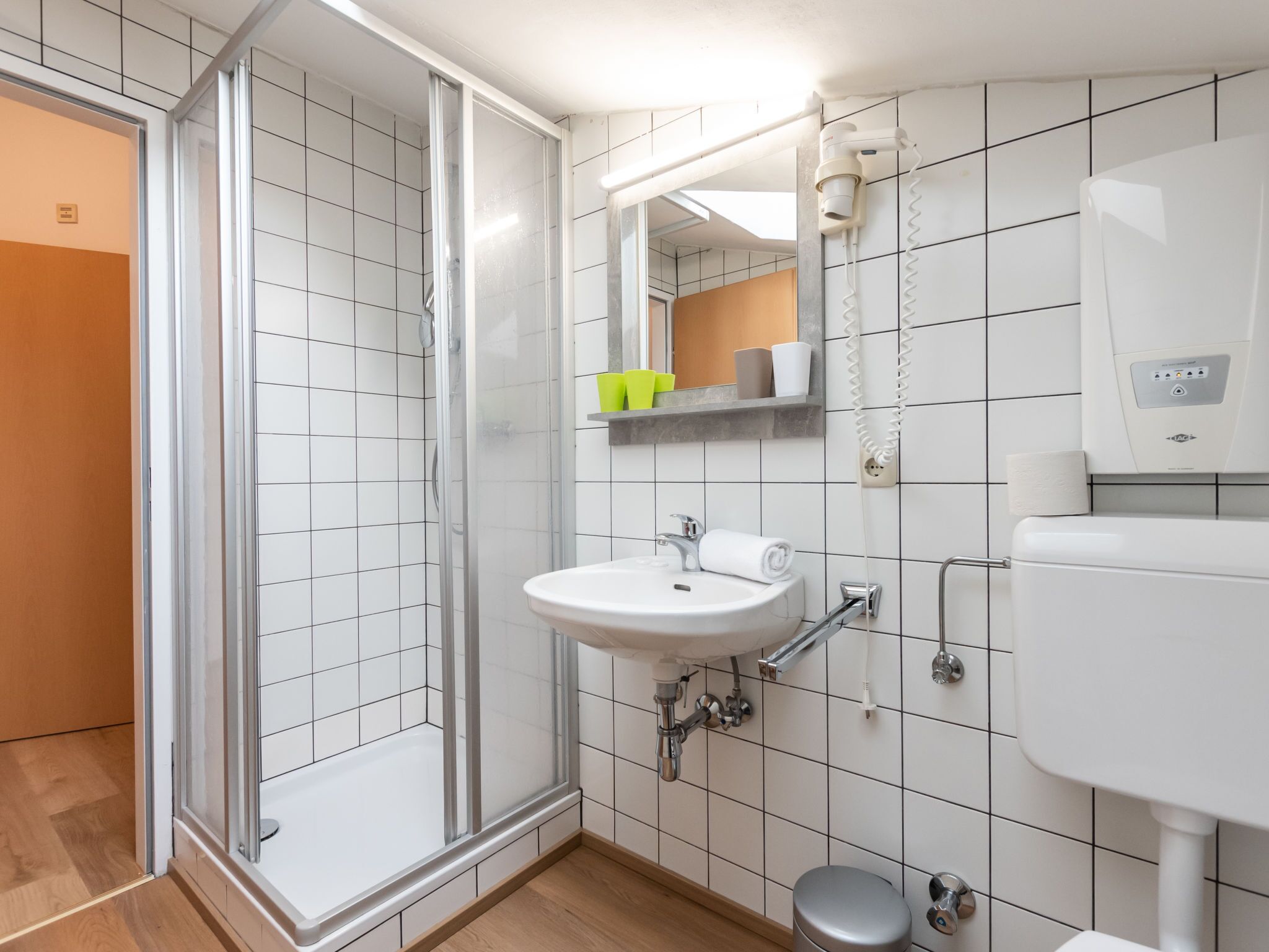 Ein modernes Badezimmer mit einer einteiligen Duschkabine, einem weißen Waschbecken und einer Toilette.