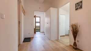 A hallway with wooden flooring, white walls, and a door leading to another room. - Alpenchalets by Interhome (Zell am See)