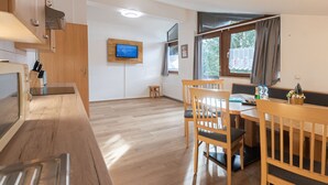 A modern kitchen with wooden cabinets, a built-in oven, and a TV mounted on the wall. - Alpenchalets by Interhome (Zell am See)