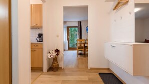 A narrow hallway with a kitchen on the left, a dining area with a table and chairs in the center, and a white cabinet on the right. - Alpenchalet by Interhome (Zell am See)