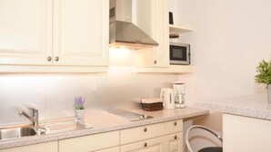 A kitchen with white cabinets, a stainless steel sink, a microwave, and a coffee maker. - Apartment Leif by Interhome (Zell am See)
