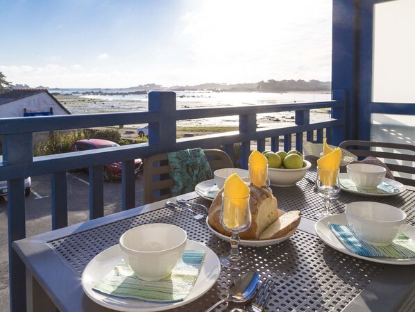 A table set for breakfast with a view of the beach and ocean.