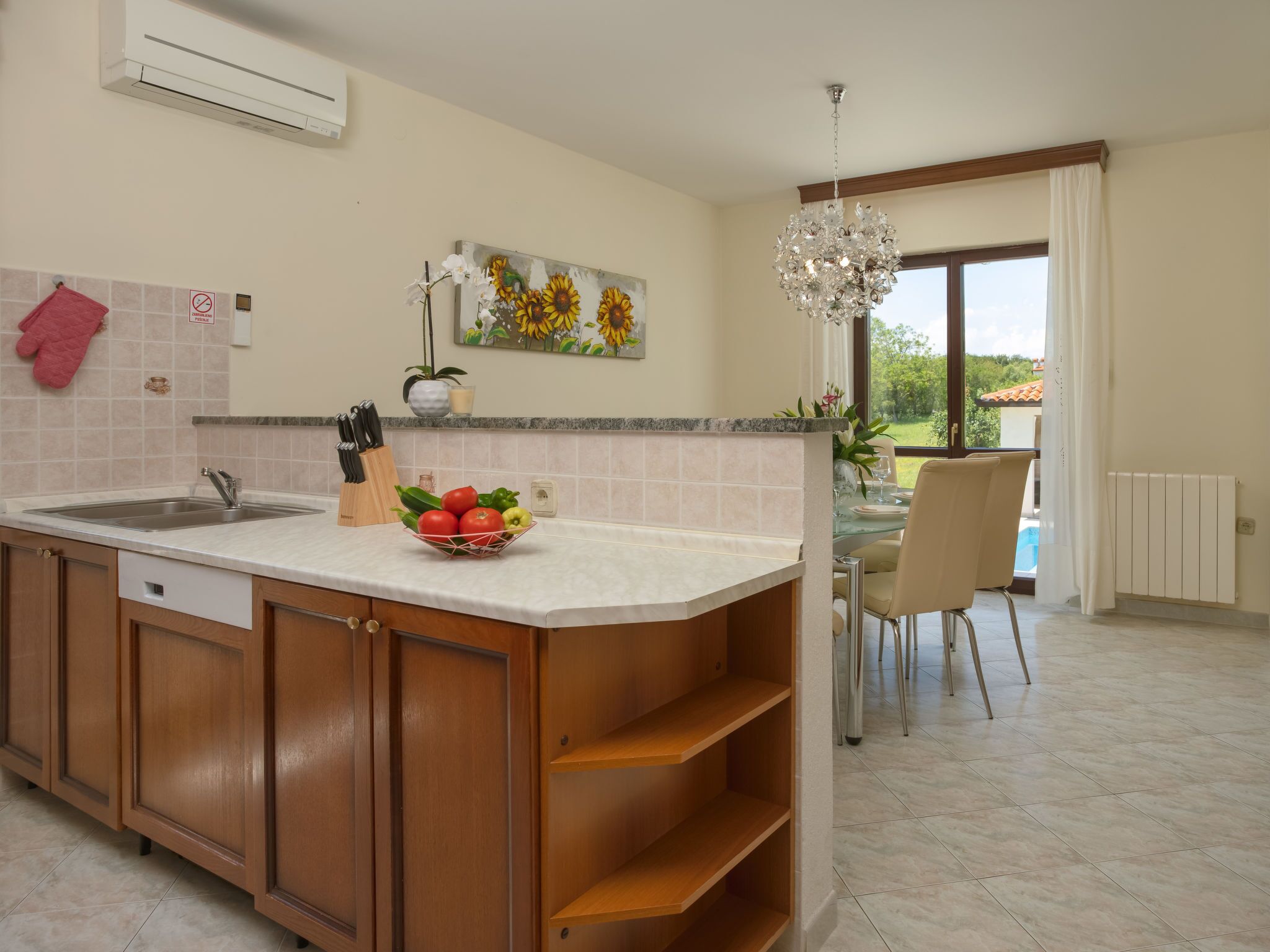 A kitchen with a sink, a fruit bowl, and a dining area with a table and chairs.