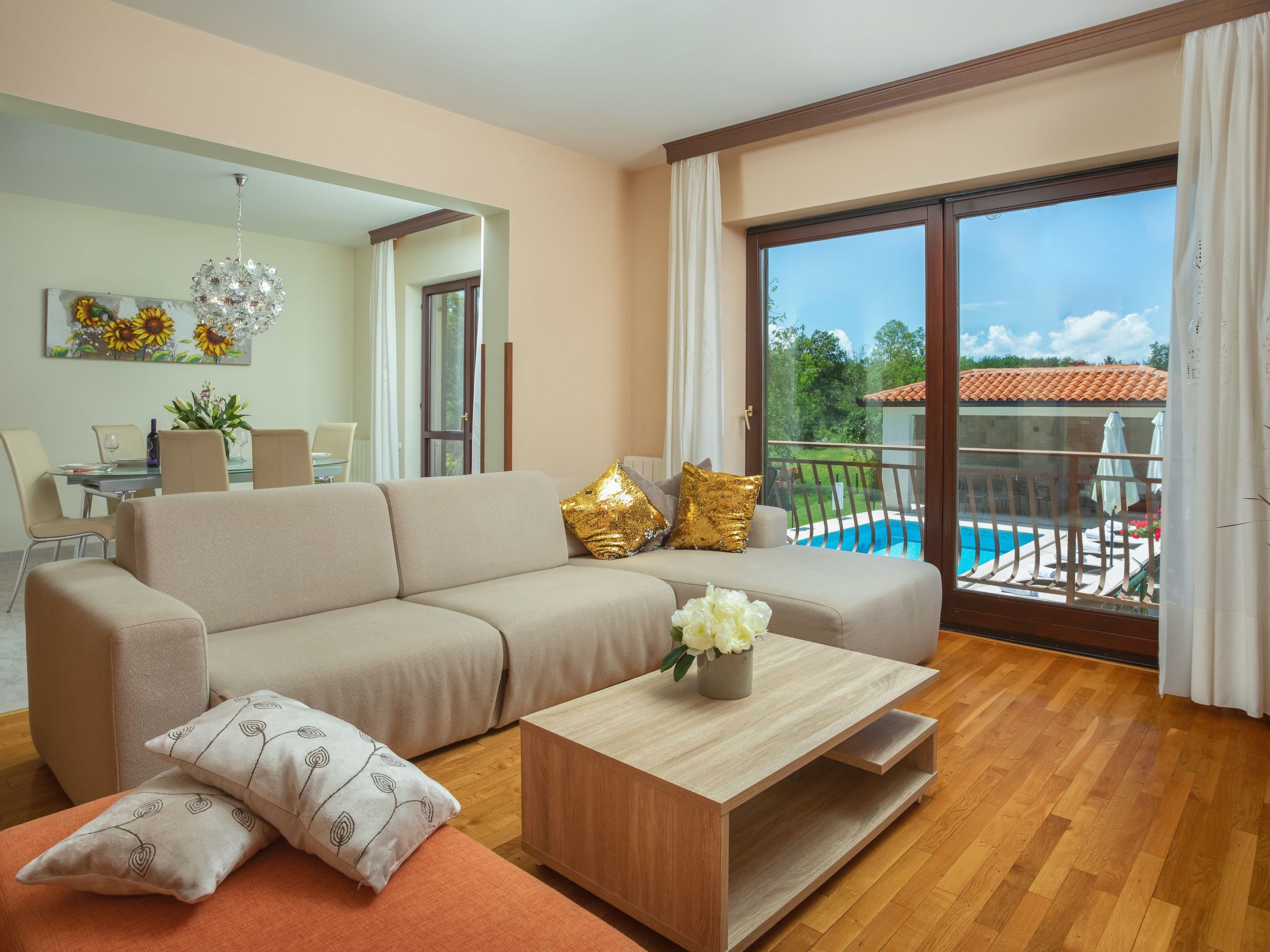A modern living room with a sofa, coffee table, and a view of a pool.