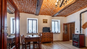 Ein Zimmer mit einem Holzesstisch, Stühlen, einem Fernseher und einem Kamin.