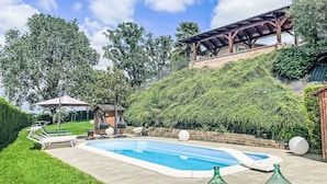 Ein Schwimmbecken mit Liegestühlen und einer Pergola.