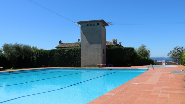 A swimming pool with clear blue water, surrounded by a tiled deck. - Bellavista by Interhome (Bardolino)