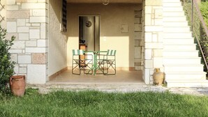 A covered outdoor seating area with a table and chairs, a potted plant, and a staircase leading to an upper level. - Bellavista by Interhome (Bardolino)
