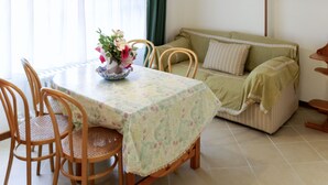 A dining area with a round table, chairs, a vase of flowers, and a sofa. - Bellavista by Interhome (Bardolino)