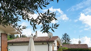 A patio with a table and chairs, a white umbrella, and a small decorative item. - Panoramico by Interhome (Bardolino)