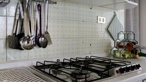 A kitchen with a gas stove, hanging kitchen utensils, and a wine rack. - Panoramico by Interhome (Bardolino)