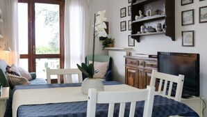 A room with a bed, a television, a dining table, and chairs. - Panoramico by Interhome (Bardolino)