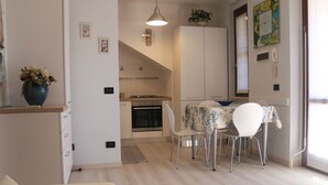 Cocina moderna con comedor, que incluye estufa, horno y sillas alrededor de una mesa.