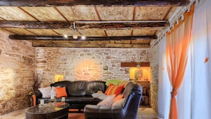 A cozy stone-walled room with a leather sofa, a round wooden table, and a small lamp. - Vacation home Bozac by Interhome (Pula/Vodnjan)