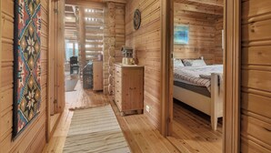 L'intérieur d'une cabane en bois, avec un couloir menant à une chambre à coucher.