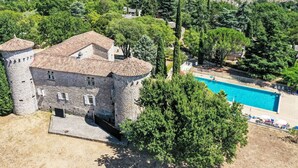 Un castillo con piscina rodeado de árboles.