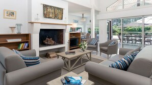 Un salon spacieux doté d’une cheminée, de sièges confortables et d’un balcon aménagé avec du mobilier d’extérieur.