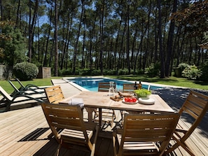 A wooden deck with a pool table, chairs, and a table set with food and drinks. - Clairière aux Chevreuils by Interhome (Moliets)