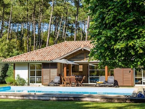 A house with a swimming pool, outdoor furniture, and a view of trees.