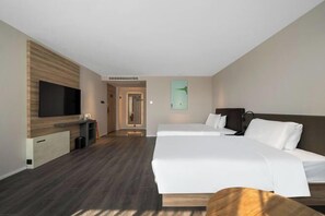 A hotel room with a bed, a TV, a small desk, and a door leading to another room. - HanTing Hotel (Xiamen Airport Wuyuan Bay) (Xiamen)