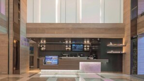 A modern hotel lobby with a reception desk, digital display, and a seating area. - HanTing Hotel (Xiamen Airport Wuyuan Bay) (Xiamen)