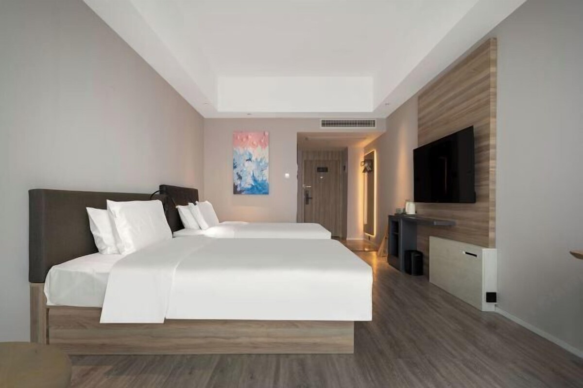 A modern hotel room with a large bed, a flat-screen TV, and a minimalist design.